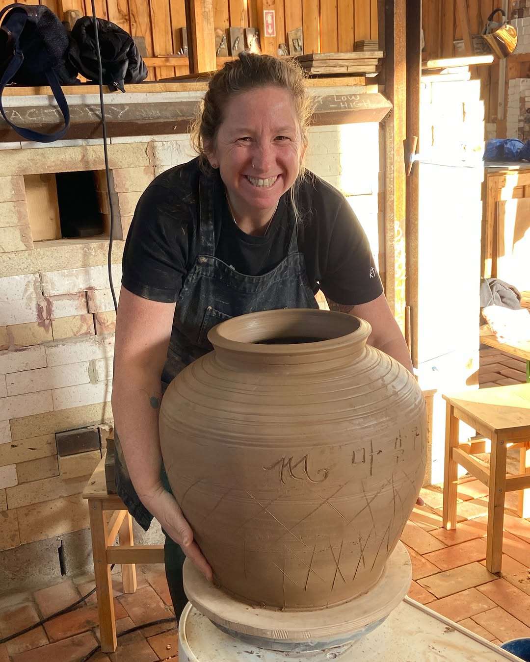 Magali Kivatinetz behind a large freshly thrown jar in the studio.