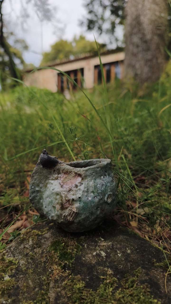A small wood-fired ceramic vessel resting in the grass at Can Brull.